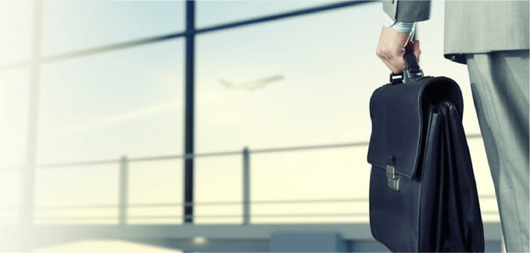 Back view of businessman at airport with suitcase in hand