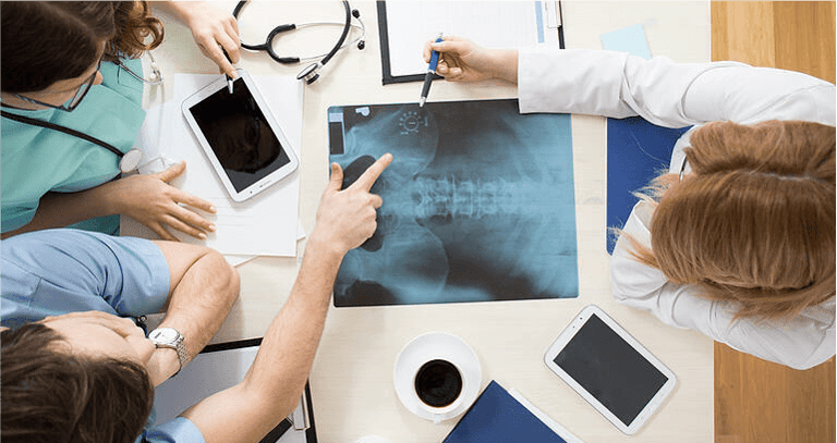 Doctors sitting around the table and interpreting x-ray image
