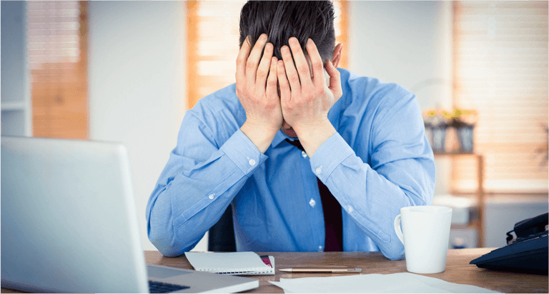 Stressed businessman with head in hands at office