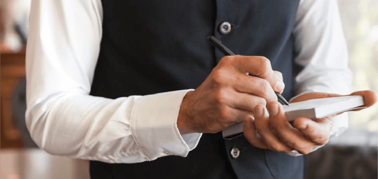 Waiter taking an order wearing a waistcoat in a fancy restaurant